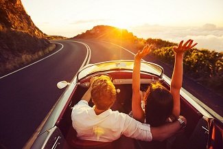 A couple typical of Drawing Down the Moon Matchmaking enjoy a date in a vintage sports car at sunset