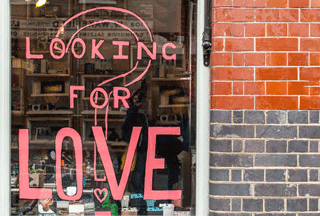 Photo of shop window with sign Looking For Love Reasons You Need to Date a Shorter Man Blog Matchmaking DDM